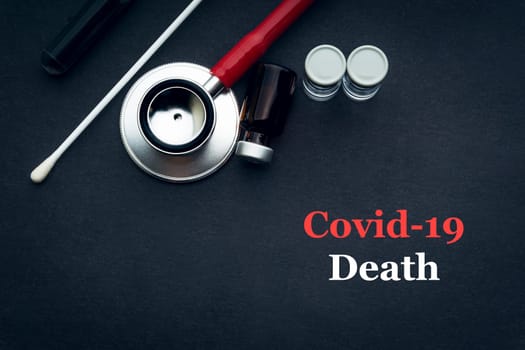 COVID-19 or CORONAVIRUS DEATH text with stethoscope, medical swab and vial on black background. Covid-19 or Coronavirus concept.
