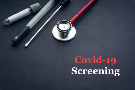 COVID-19 or CORONAVIRUS SCREENING text with stethoscope, medical swab and blood sample tube on black background. Covid-19 or Coronavirus concept.