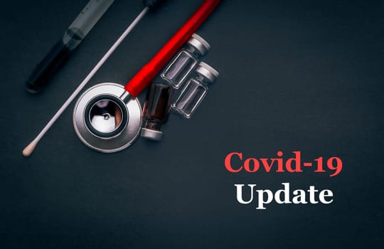 COVID-19 or CORONAVIRUS UPDATE text with stethoscope, medical swab and vial on black background. Covid-19 or Coronavirus concept.