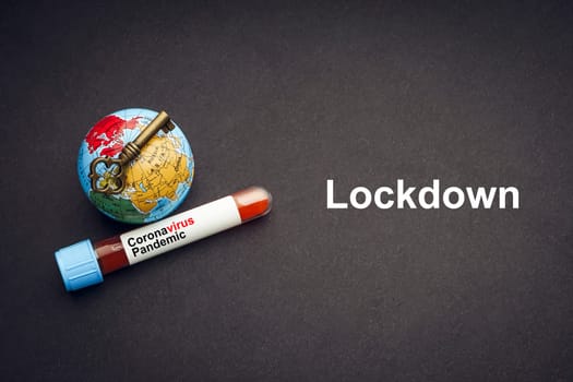 CORONAVIRUS LOCKDOWN text with world globe, key and Blood test vacuum tube on black background. Covid-19 or Coronavirus Concept