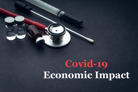 COVID-19 or CORONAVIRUS ECONOMIC IMPACT text with stethoscope, medical swab and vial on black background. Covid-19 or Coronavirus concept.