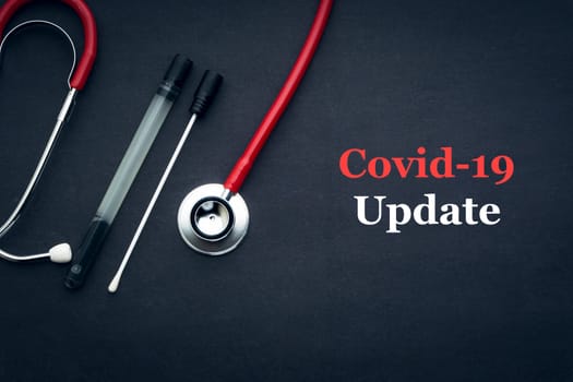 COVID-19 or CORONAVIRUS UPDATE text with stethoscope and medical swab on black background. Covid-19 or Coronavirus concept.