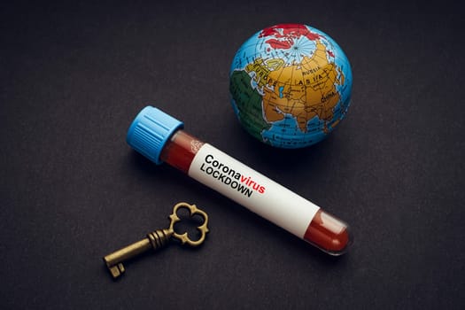 CORONAVIRUS LOCKDOWN text with world globe, key and Blood test vacuum tube on black background. Covid-19 or Coronavirus Concept