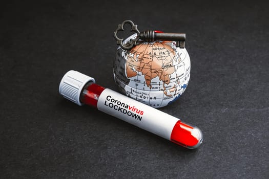CORONAVIRUS LOCKDOWN text with world globe, key and Blood test vacuum tube on black background. Covid-19 or Coronavirus Concept