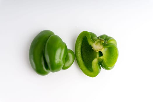 Fresh green bell peppers (capsicum) on a white background. Selective focus and crop fragment
