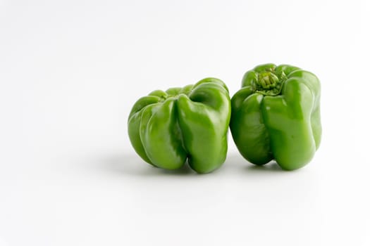 Fresh green bell peppers (capsicum) on a white background. Selective focus and crop fragment