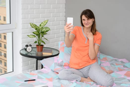 Girl with a smile looks at the screen of a smartphone while communicating by video connection