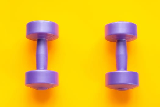 Two purple dumbbells lie separately on a yellow background