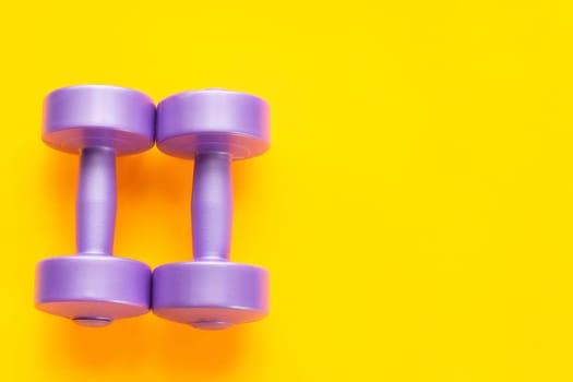 Two purple dumbbells lie next to a yellow background