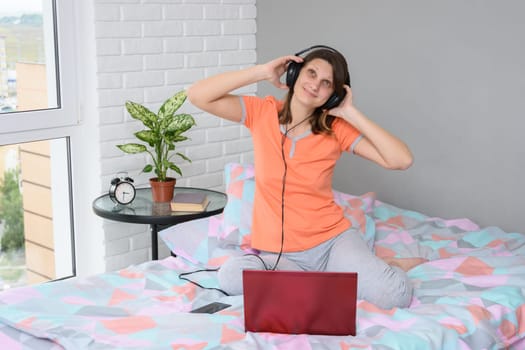 The girl put on her headphones, connected them to the computer and is listening to music happily