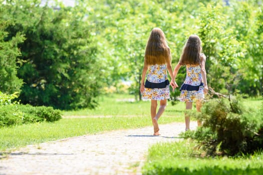 Two girls walk along a path in a beautiful city park
