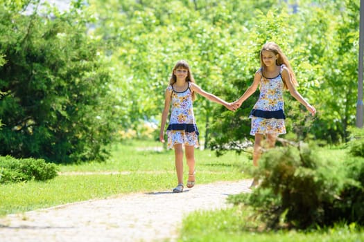 Two sisters together walk in a beautiful city park