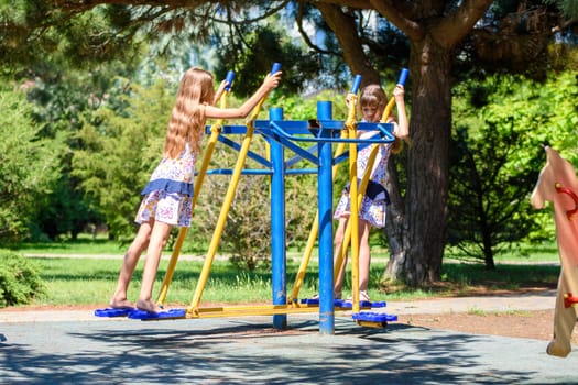 Two girls warm up on exercise machines in the park