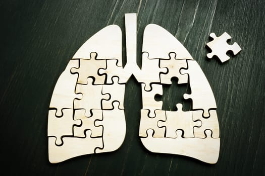 Lung cancer or respiratory disease concept. Wooden puzzle on the dark surface.