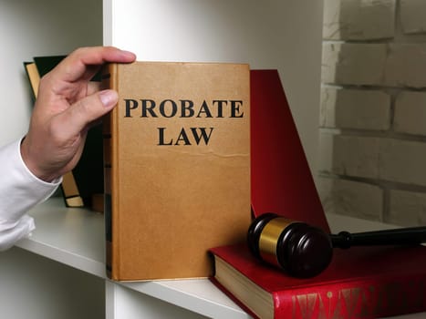 Lawyer takes a book Probate law from a shelf.