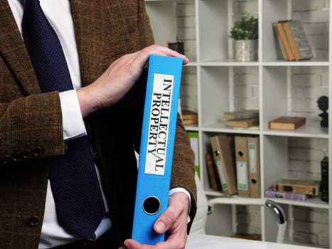 The lawyer holds a folder with the inscription Intellectual Property.