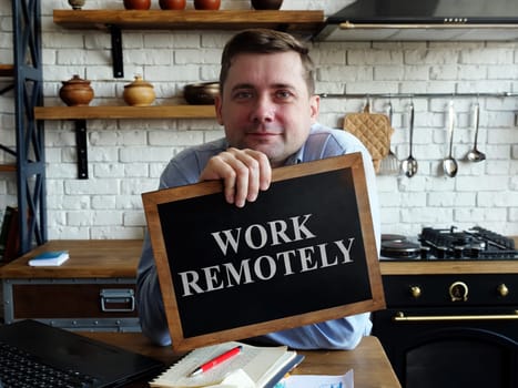 Happy man holds work remotely sign.