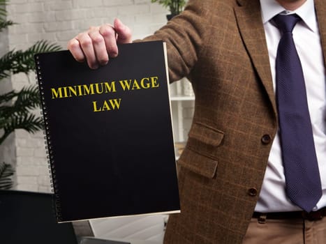 A man in a suit shows a book minimum wage law.
