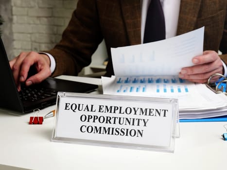 A man works at a table with a tablet Equal Employment Opportunity Commission EEOC.