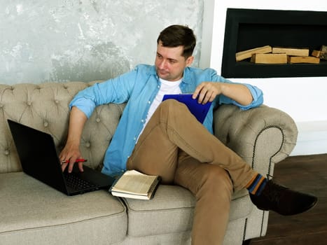 Remote work. A young guy works at home with a laptop and documents.