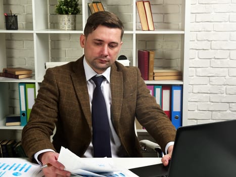 Businessman in a suit works with documents in the office. The workplace of the manager.