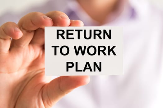 Closeup on businessman holding a card with text Returning To Work Plan, business concept image with soft focus background