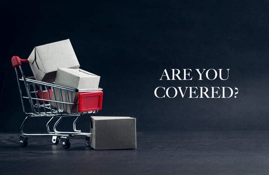 Shopping cart with words ARE YOU COVERED on dark background. Business, Copy space and online shopping concept. Selective focus