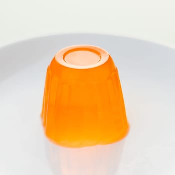 Close up of a orange gelatin on a white plate.