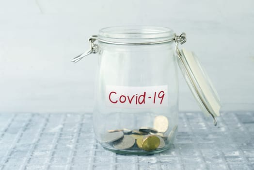 Coins in glass money jar with covid19 label, financial concept.