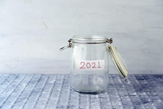 Coins in glass money jar with 2021 label, financial concept.