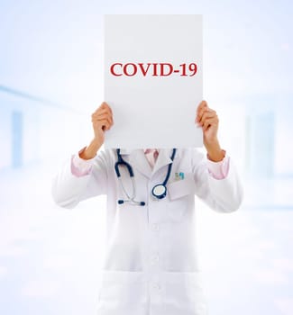 Medical staff holding a card with covid 19 on it.