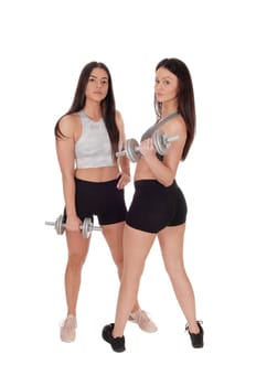 Two beautiful young woman standing in workout outfits in the studio.working out with there dumbbells, isolated for white background.