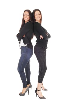 Two beautiful young woman standing back to back in jeans and heels.looking at the camera, isolated for white background.