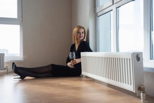 girl with a beautiful smile and a glass of wine sitting on the floor