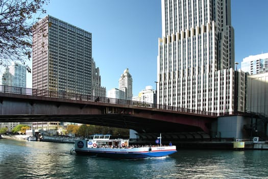 CHICAGO  ILLINOIS/USA-OCTOBER 14 2015: Chicago river with tourist boat under Columbus Bridge with tall surrounding buildings on October 14 2015  Chicago  Illinois