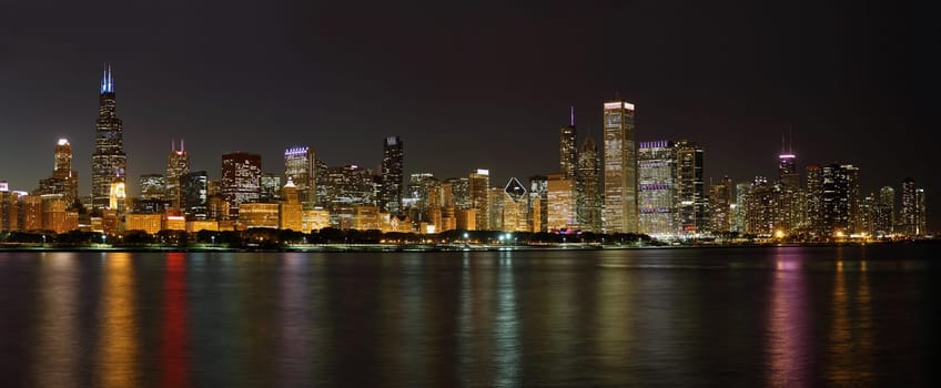 The Chicago skyline and waterfront at night with illuminated buildings reflected in the water of Lake Michigan