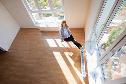 View from above on a large room with large windows where a girl sits on a chair