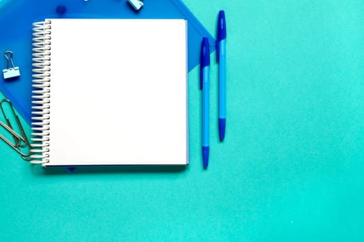 Blue school or office suplies against light blue background with copy space. Back to school or business concept, top view. Flat lay