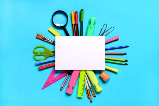 Group of School or office supplies around a notepad on light blue background. Back to school concept. Space for text. Flat lay. Mock up