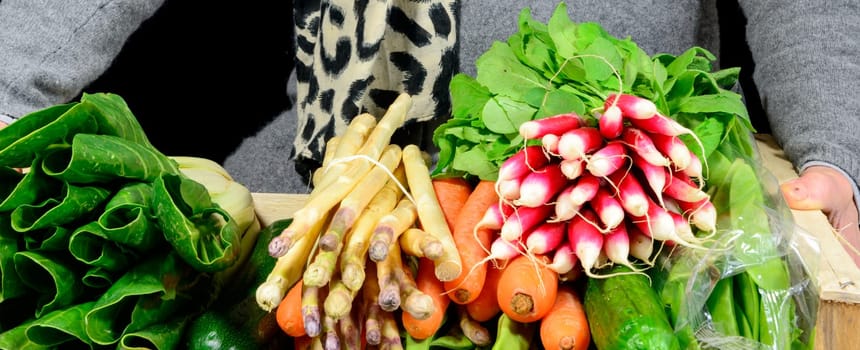 small crate with various seasonal vegetables on black background