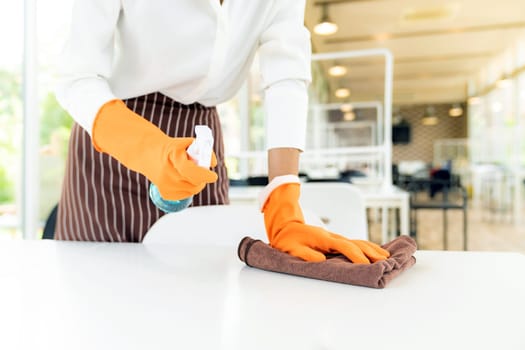 Close up of waitress hand cleaning table with alcohol and wet wipe before welcome customer. New normal hygiene restaurant concept.