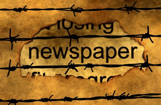 Newspaper text on paper hole against barbwire