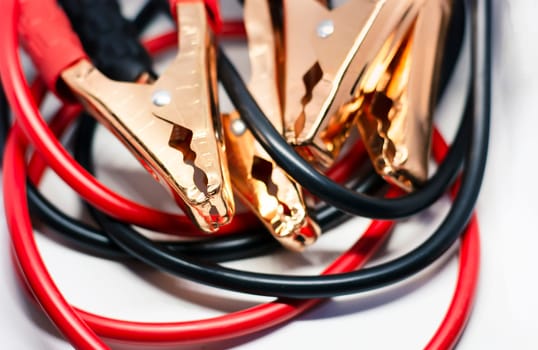 Close up of red and black car battery jumper cable, isolated on white background. Boost cable. Focus on metal