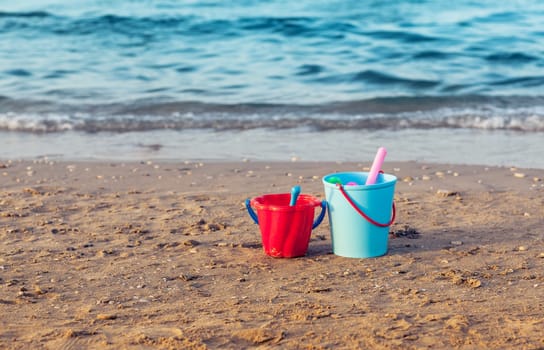 Child's bucket, spade and other toys in the sand on empty beach