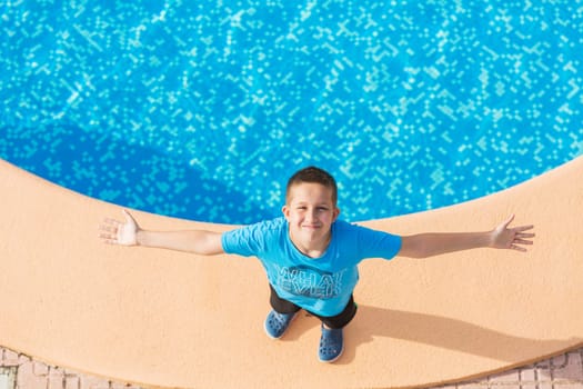 Boy standing at the swimming pool and enjoying the holiday - top view