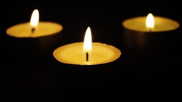 three memorial candles in darkness