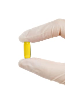 yellow pill in hand with medical gloves