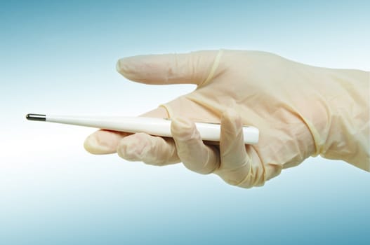 hand with medical gloves and thermometer on light blue surface