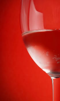 red drink in the wine glass on red background