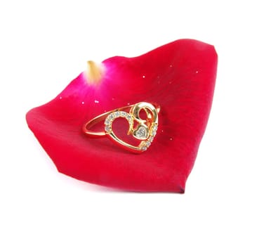 wedding ring with rose petal over white surface